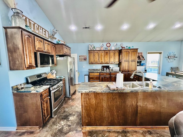 kitchen with sink, stone countertops, lofted ceiling, and appliances with stainless steel finishes