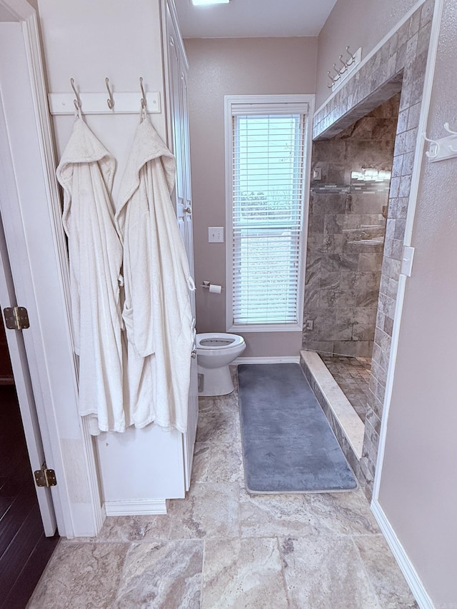 bathroom featuring tiled shower and toilet