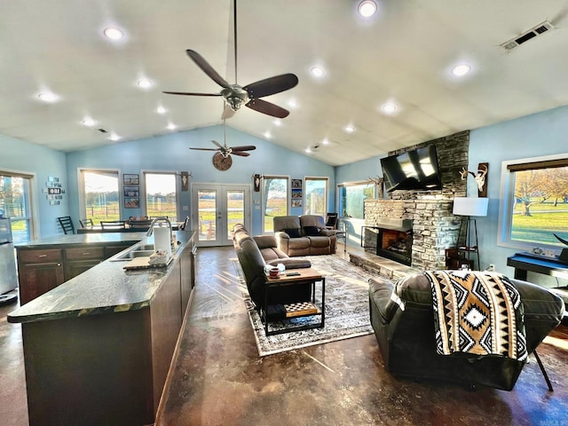 living room with french doors, a stone fireplace, sink, vaulted ceiling, and ceiling fan