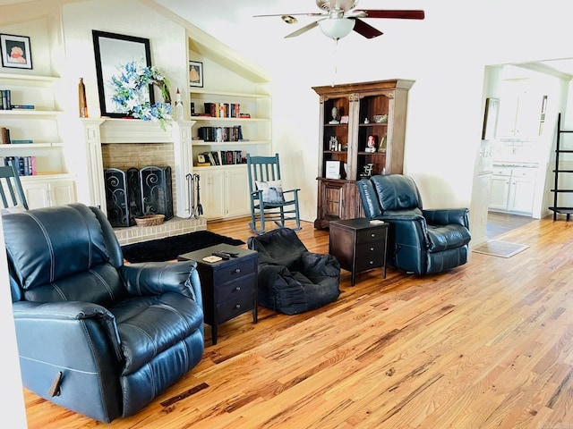 living room with ceiling fan, light hardwood / wood-style flooring, and a brick fireplace