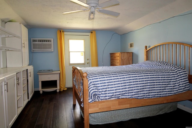 bedroom with ceiling fan, dark hardwood / wood-style flooring, a wall unit AC, a textured ceiling, and vaulted ceiling