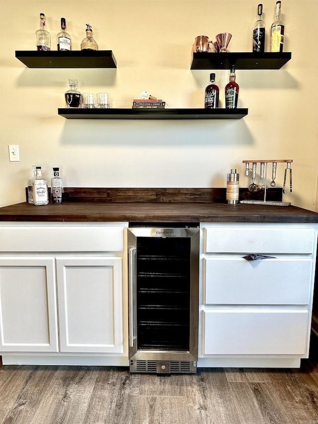 bar featuring white cabinets, beverage cooler, and hardwood / wood-style flooring