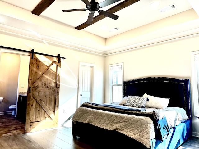 bedroom featuring a barn door, hardwood / wood-style flooring, ceiling fan, and connected bathroom