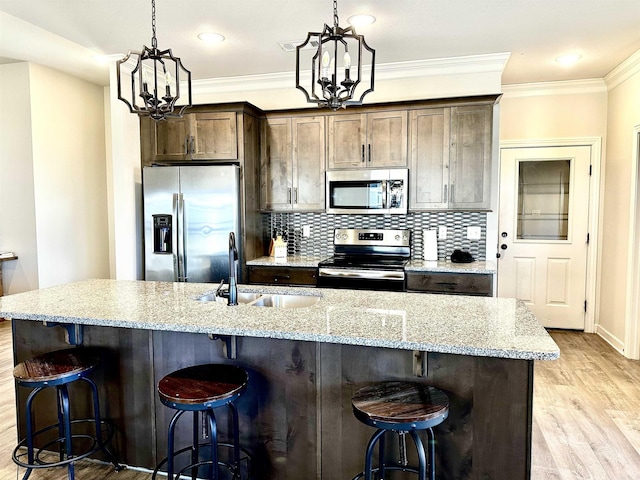 kitchen with sink, dark brown cabinetry, stainless steel appliances, and a chandelier