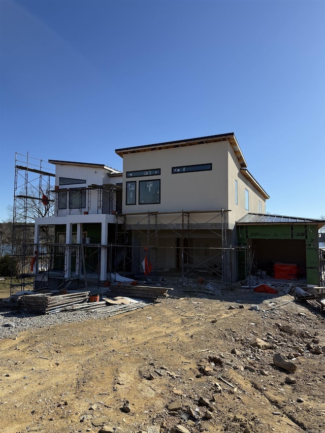 rear view of property with stucco siding and metal roof