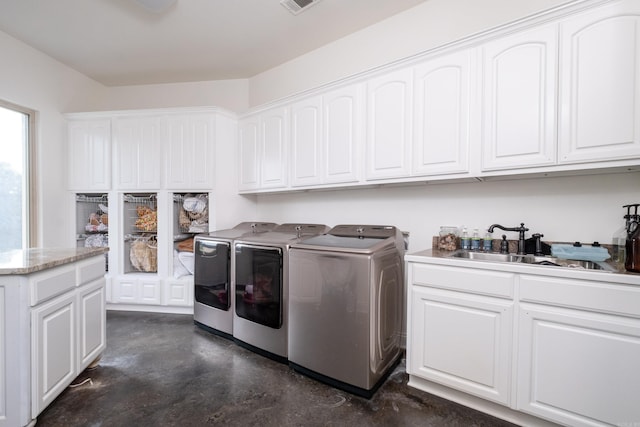 laundry area featuring cabinets, separate washer and dryer, and sink