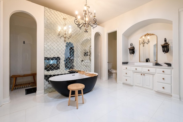 bathroom with a bath, tile patterned floors, a chandelier, toilet, and vanity