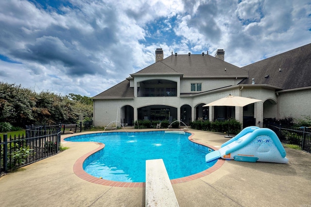 view of pool with ceiling fan, a diving board, a patio area, and a water slide