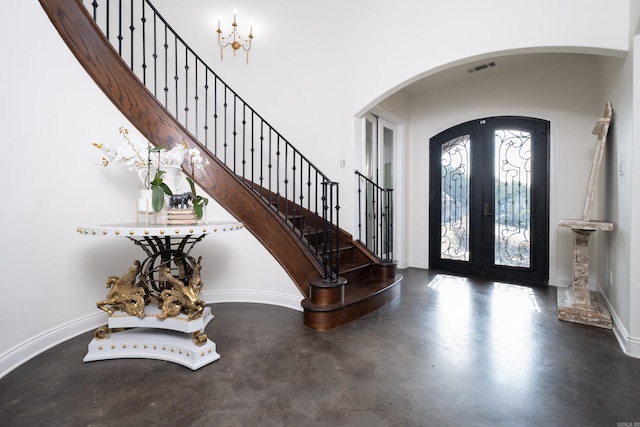 entrance foyer with concrete flooring, french doors, and an inviting chandelier