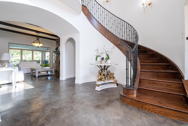 staircase featuring beam ceiling and concrete flooring