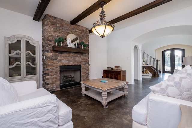 living room featuring beamed ceiling, french doors, and a fireplace