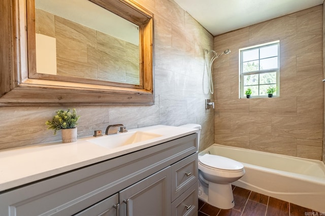 full bathroom with tiled shower / bath, vanity, tile walls, and toilet