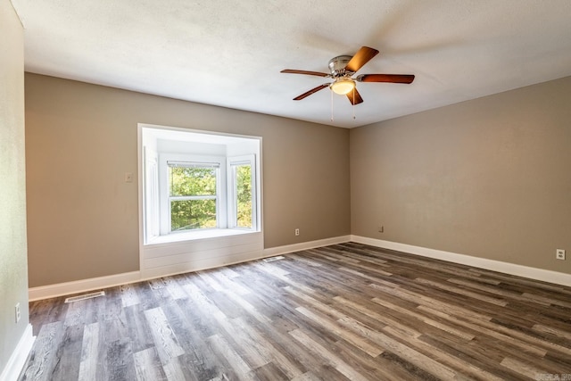 empty room with a textured ceiling, ceiling fan, and dark wood-type flooring