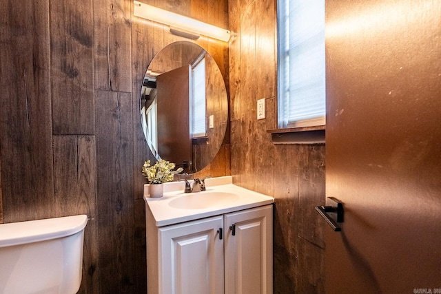 bathroom with wood walls, vanity, and toilet