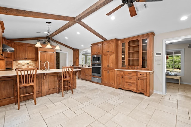 kitchen with sink, vaulted ceiling with beams, built in appliances, a breakfast bar, and exhaust hood