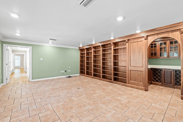 unfurnished room featuring built in shelves, ornamental molding, and indoor bar