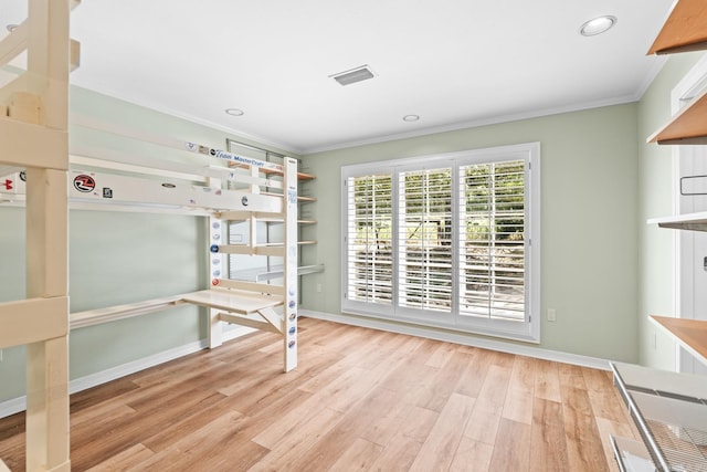 unfurnished bedroom with crown molding and light wood-type flooring