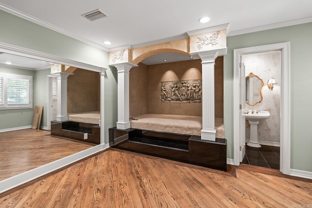 interior space with decorative columns, ornamental molding, and hardwood / wood-style flooring