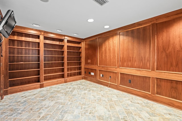 interior space featuring built in shelves and wooden walls