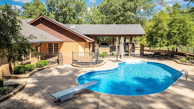 view of swimming pool featuring a diving board and a patio