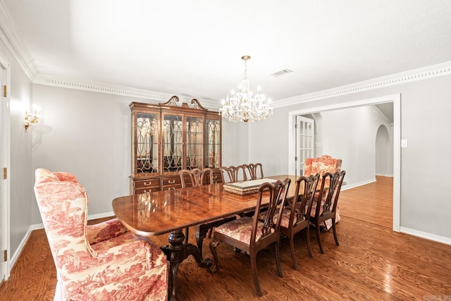 dining space featuring ornamental molding, a chandelier, and hardwood / wood-style flooring