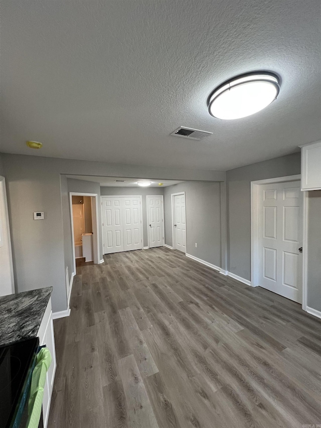 unfurnished living room with wood-type flooring and a textured ceiling