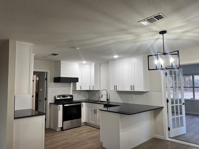 kitchen featuring sink, kitchen peninsula, stainless steel electric range oven, decorative light fixtures, and white cabinetry