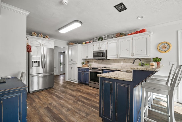 kitchen featuring visible vents, blue cabinetry, a peninsula, stainless steel appliances, and a sink