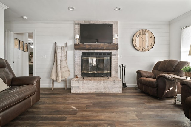 living room featuring dark hardwood / wood-style flooring, ornamental molding, and a brick fireplace