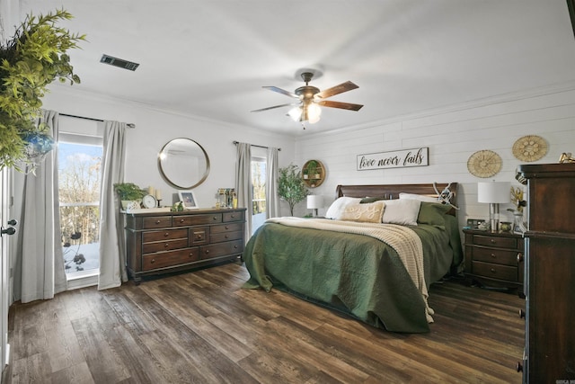 bedroom featuring ceiling fan, wood walls, ornamental molding, and dark wood-type flooring