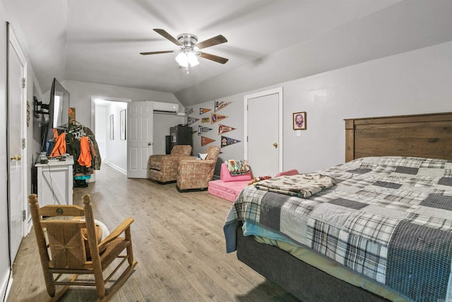 bedroom with an AC wall unit, light wood-style flooring, a ceiling fan, and vaulted ceiling