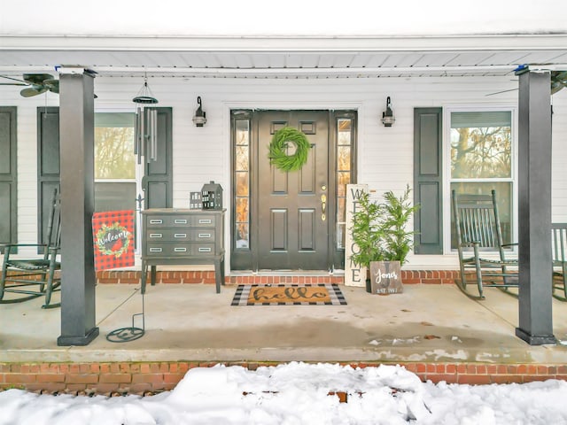 snow covered property entrance with covered porch