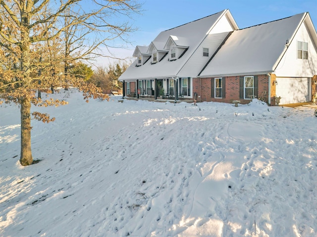 snow covered back of property with brick siding and a garage