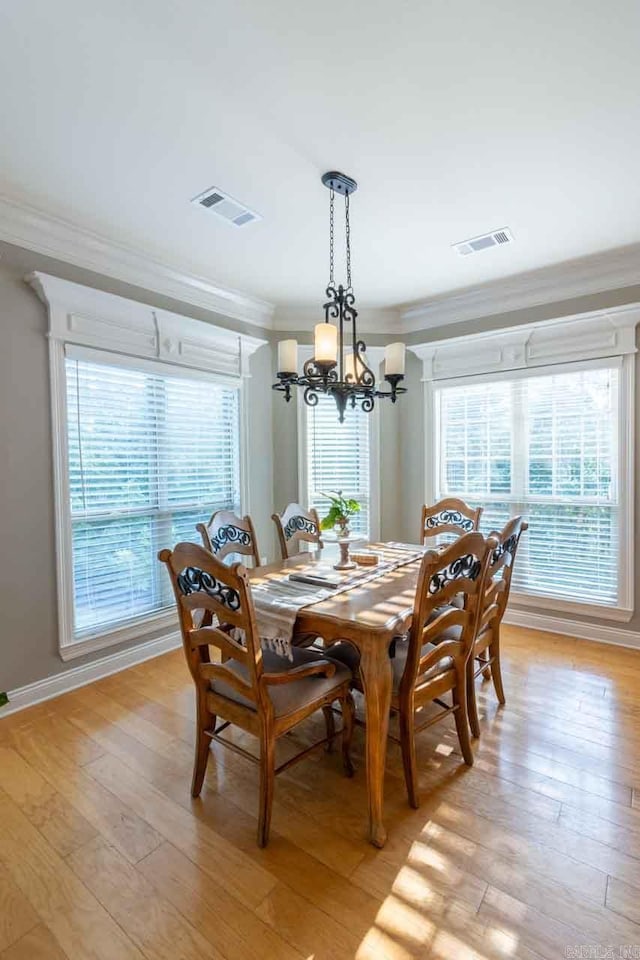 dining area with ornamental molding, a chandelier, and light wood-type flooring