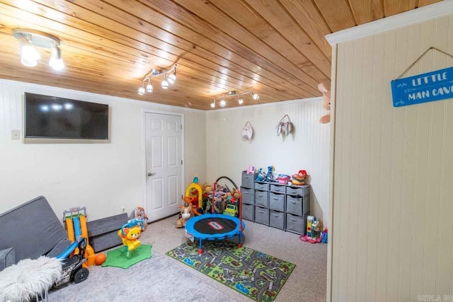 rec room featuring carpet flooring, wooden walls, wood ceiling, and track lighting