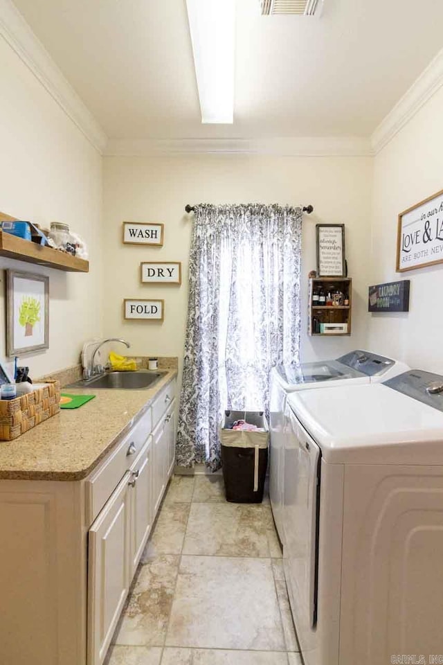 laundry room featuring washing machine and clothes dryer, crown molding, sink, and cabinets