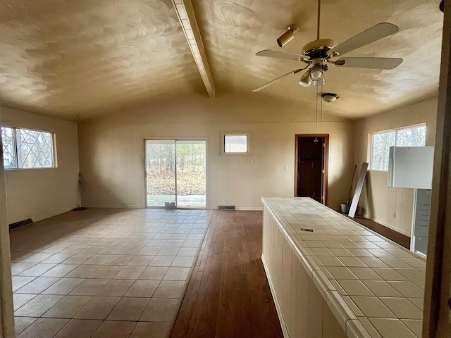 interior space featuring a textured ceiling, lofted ceiling with beams, light hardwood / wood-style flooring, and ceiling fan