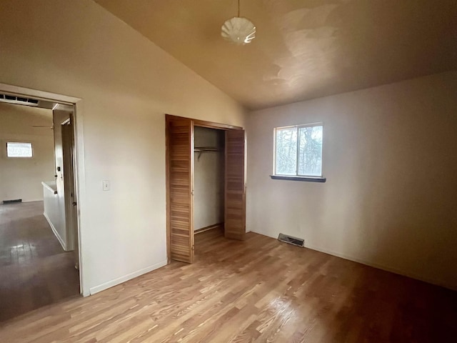 unfurnished bedroom featuring light wood-type flooring, a closet, and lofted ceiling