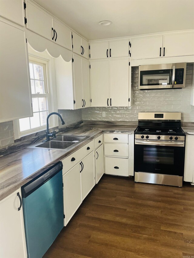 kitchen featuring appliances with stainless steel finishes, backsplash, dark wood-type flooring, sink, and white cabinets