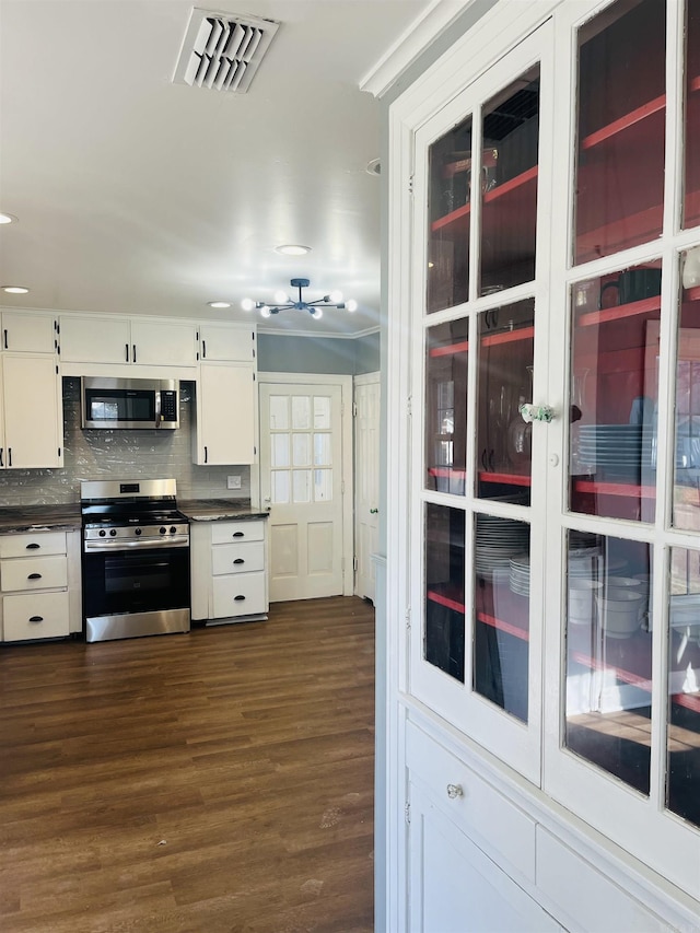 kitchen featuring decorative backsplash, appliances with stainless steel finishes, dark hardwood / wood-style floors, and white cabinetry