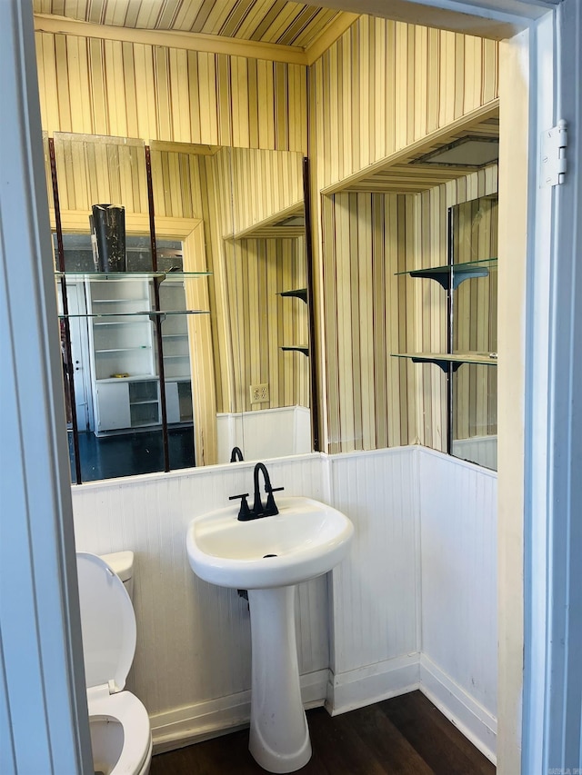 bathroom with wood walls, wood-type flooring, and toilet