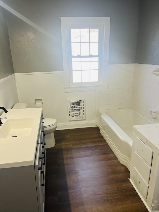 bathroom featuring hardwood / wood-style floors, vanity, a bath, toilet, and heating unit