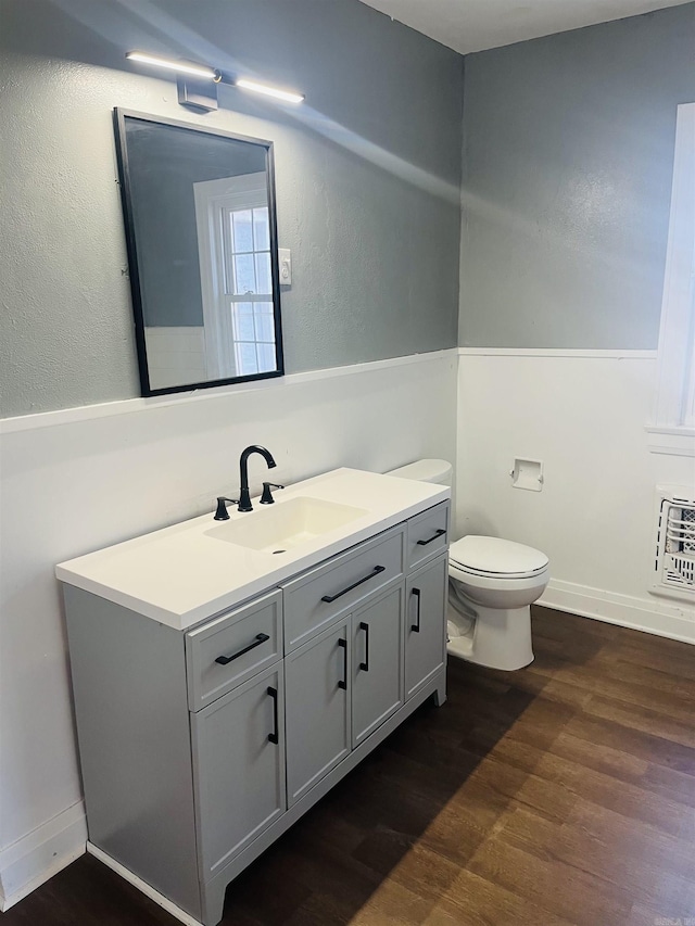 bathroom with hardwood / wood-style flooring, vanity, toilet, and heating unit