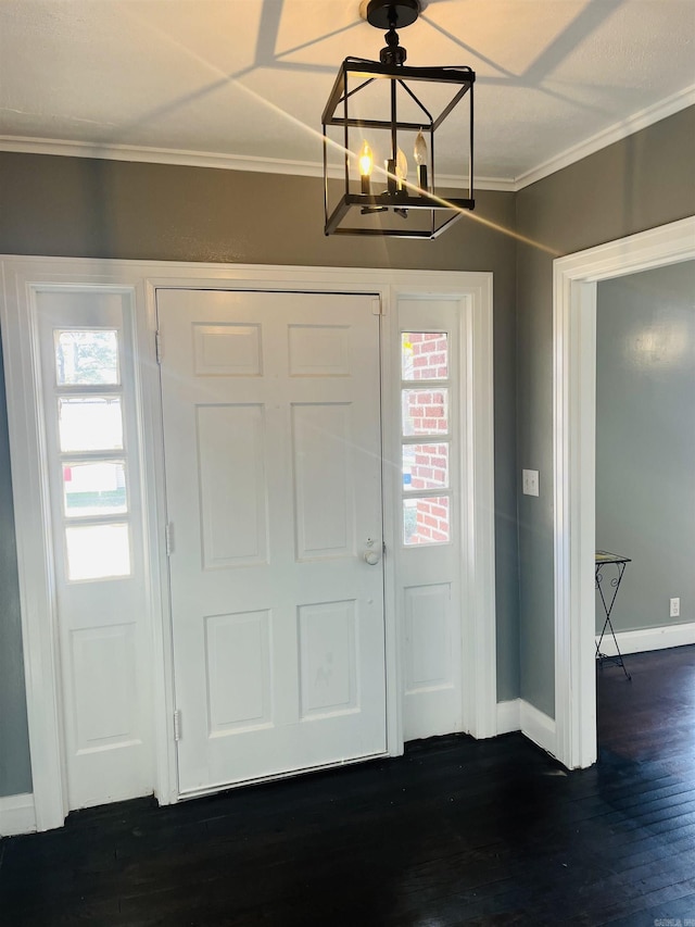 foyer featuring dark hardwood / wood-style flooring, ornamental molding, and an inviting chandelier