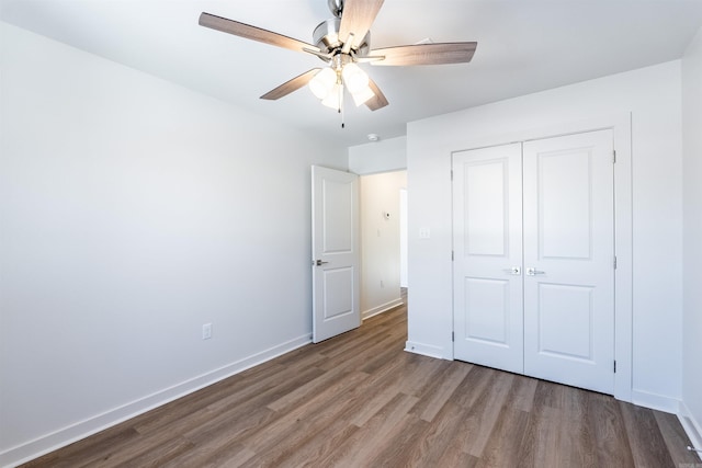 unfurnished bedroom with ceiling fan, a closet, and hardwood / wood-style flooring