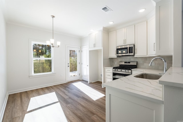 kitchen with sink, light stone counters, decorative light fixtures, white cabinets, and appliances with stainless steel finishes