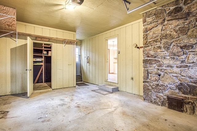 miscellaneous room featuring concrete flooring and wood walls