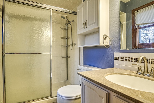 bathroom with vanity, toilet, an enclosed shower, and decorative backsplash