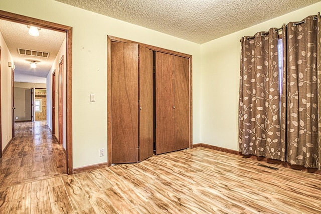 unfurnished bedroom with a closet, a textured ceiling, and light wood-type flooring