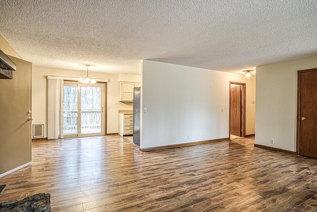 unfurnished living room with an inviting chandelier and hardwood / wood-style flooring